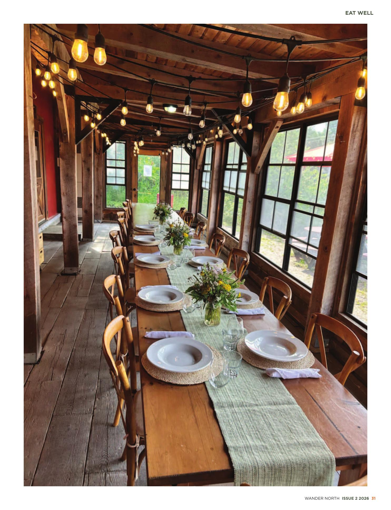 A long harvest table set inside a timber-framed barn